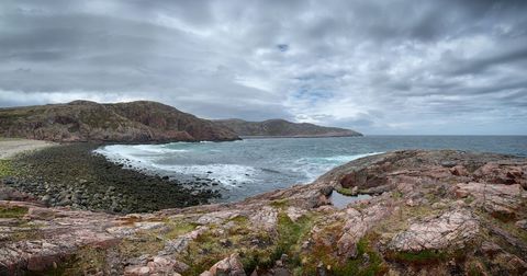 Tranquil rocky coastal beach landscape under dramatic sky