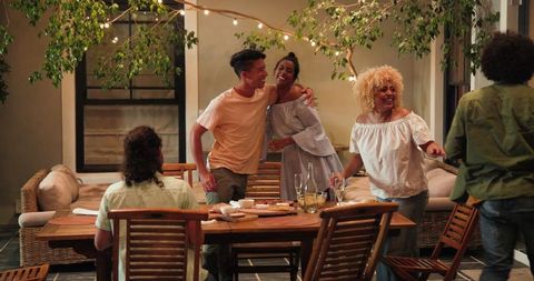 Friends Cleaning Up After Outdoor Dinner Party Near Lights