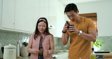 Couple preparing fresh herbs and grinding spices in bright modern kitchen, home cooking