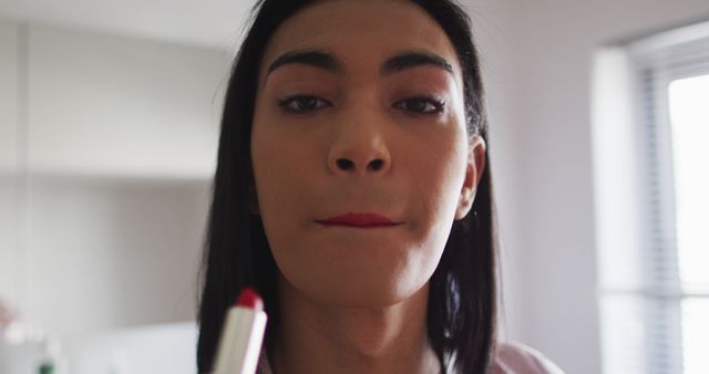 Biracial gender fluid person standing in bathroom and using a lipstick - Download Free Stock Photos Pikwizard.com