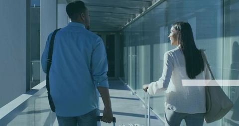 Couple traveling through modern airport glass walkway