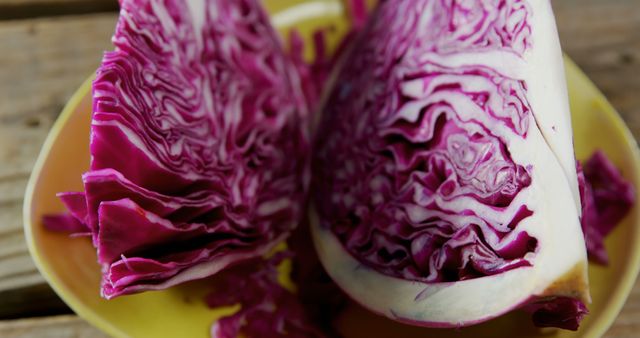 Sliced purple cabbage on yellow plate showcasing intricate natural patterns and vibrant color. Perfect for food blogs, nutrition articles, organic produce promotions, vegetarian and vegan recipe illustrations, and culinary magazines highlighting fresh and healthy ingredients.