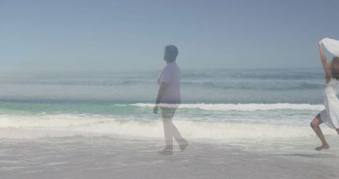 Senior woman walking along shoreline with flowing scarf, double exposure seascape