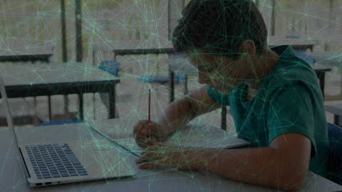 Boy Engaged in E-Learning with Laptop and Book in Classroom Setting