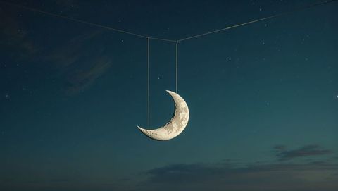 Surreal crescent moon sculpture suspended in night sky