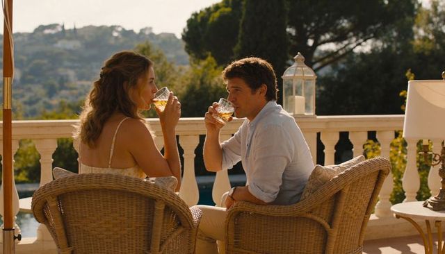 Sunlit villa couple sipping cocktails on terrace in wicker chairs during golden hour