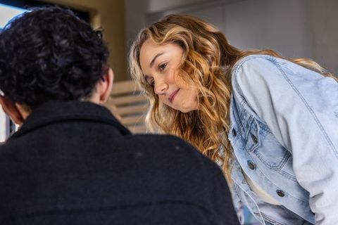 Young couple leaning and talking in lounge, denim jacket, candid warm moment