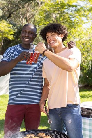 Diverse friends toasting and grilling outdoors in summer