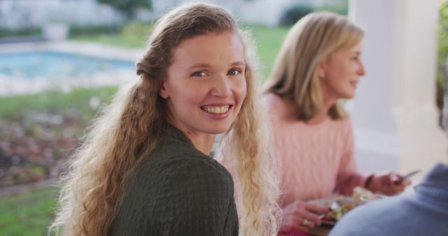 Image of happy caucasian mother turning and smiling at outdoor family dinner table. Family, domestic life and togetherness concept digitally generated image.