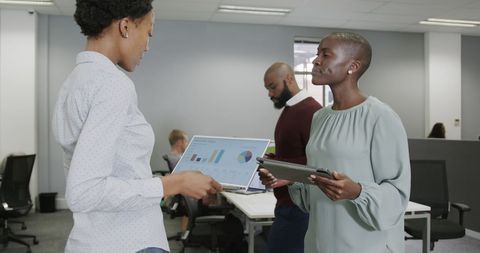 Colleagues Discussing Data with Tablets in Modern Office