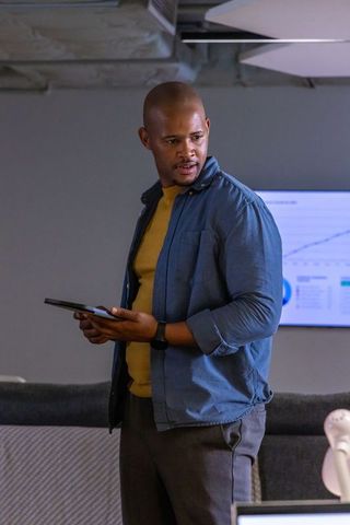 African american presenter using tablet and displaying business charts in office