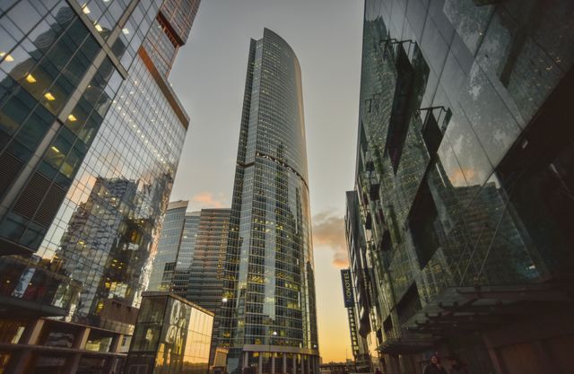 Panoramic view of a modern cityscape featuring numerous tall skyscrapers and glass buildings at sunset. Ideal for use in business, real estate, travel, and urban development projects showcasing city living and architectural innovation.