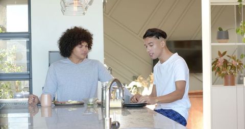 Diverse Father and Son Eating Breakfast at Modern Kitchen Island