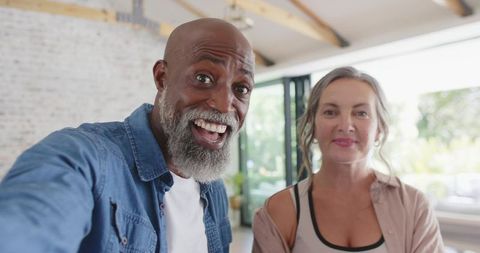 Sunlit modern home couple taking selfie smiling husband holding smartphone closeup
