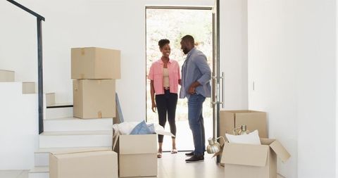 Couple Entering New House with Moving Boxes and Smiles
