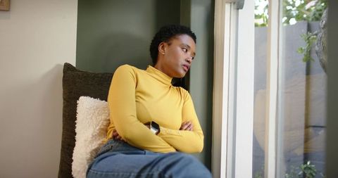 Thoughtful Woman in Cozy Chair Relaxing near Window