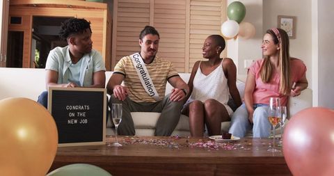 Friends Celebrating New Job with Confetti and Drinks in Cozy Living Room