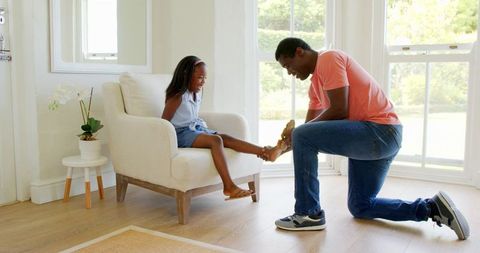 Father helping daughter try sandals home bonding moment