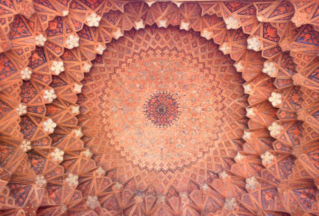 This image showcases a beautifully intricate ceiling design featuring geometric patterns typical of Persian architecture. The detailed craftsmanship displays a rich cultural heritage with traditional motifs and artistic symmetry. Ideal for use in articles about architectural design, cultural studies, history of Islamic art, and promotional materials for heritage tourism.
