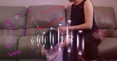 Chinese mother holding baby watching holographic data dashboard on sofa with laptop