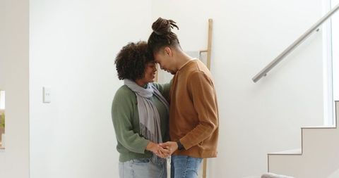 African american couple holding hands pressing foreheads in bright modern home interior
