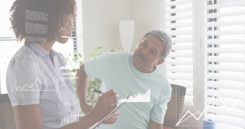 Caregiver assessing senior in sunlit living room with digital health charts and clipboard