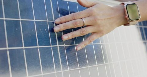 African american woman placing hand on solar panel wearing smartwatch and ring