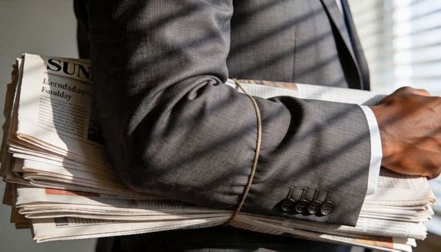 Businessman carrying newspaper bundle tied with twine, sunlight casting blinds shadows