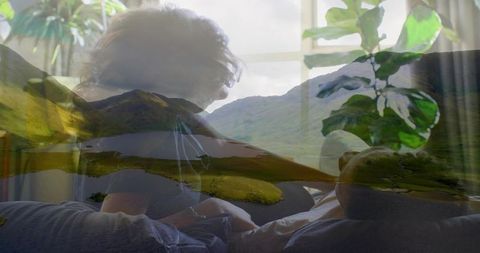Couple leaning together on sofa with dreamlike mountain lake double exposure overlay