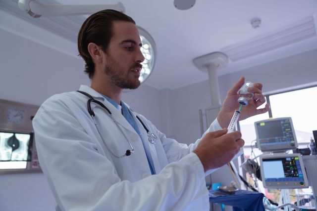 Male doctor filling syringe with medicine from ampule in a hospital operation room. Ideal for use in healthcare, medical, and hospital-related content, illustrating medical procedures, patient care, and professional healthcare services.