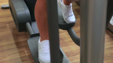 Woman Exercising on Cross Trainer in Modern Gym