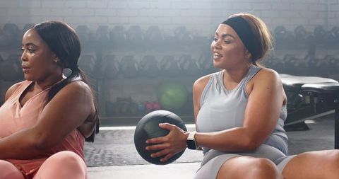 Diverse women working out together with medicine ball for core strength and teamwork