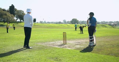 Male Cricketers Engaged in Game on Sunny Day Outdoors