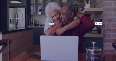 Senior Couple Embracing While Using Laptop in Modern Kitchen