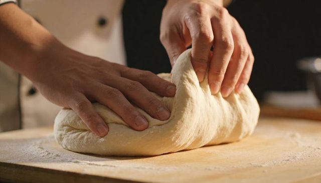 Hands Kneading Dough on Floured Wooden Board, Chef Jacket Cuff, Artisan Bread Making