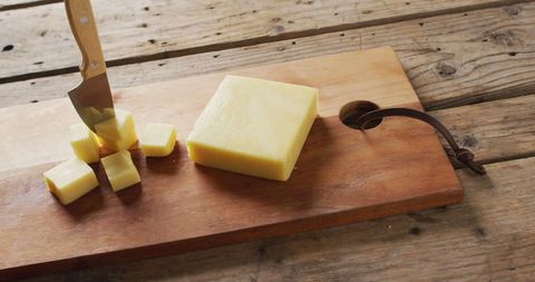 Cubes of cheese on wooden cutting board with rustic background
