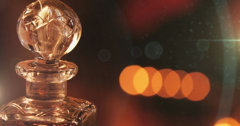 A close-up of a beautifully designed crystal decanter illuminated by the warm, nostalgic glow of Christmas lights. Ideal for concepts related to holiday entertaining, luxury and elegance in home decor, and festive celebrations. This can be used in advertisements for home goods, Christmas or holiday themed merchandise, and lifestyle magazines focusing on elegant living.
