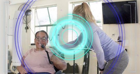 Trainer assisting wheelchair user during rehabilitation workout in bright gym studio