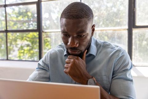 Professional Man Focusing on Laptop in Bright Office