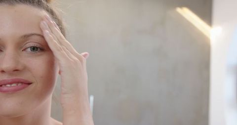 Woman practicing skincare routine at bathroom vanity