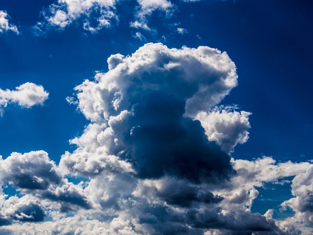 Vivid cumulus clouds forming against a clear blue sky. Ideal for weather-related content, nature photography, backgrounds, and environmental studies. Use in designs, prints, or presentations requiring scenic or dramatic sky imagery.