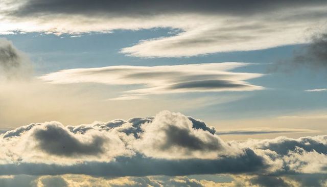 Sunlit Layered Clouds Floating Over Horizon with Lenticular and Cumulus Formations