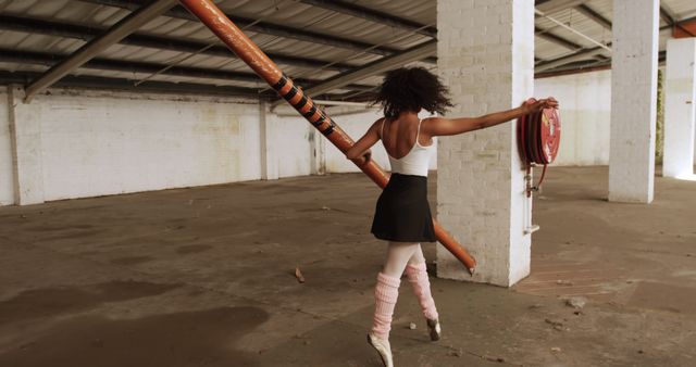 Ballet dancer practicing in an abandoned warehouse, demonstrating strength, elegance, and dedication. Ideal for concepts of perseverance, art, and unconventional practice spaces. Useful for blogs, social media, and publications focusing on dance, fitness, and personal growth.