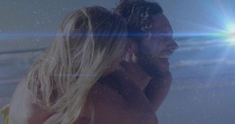 Couple Enjoying Beach Piggyback Under Sun Flare