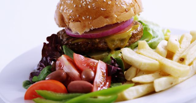 A juicy cheeseburger with lettuce, tomato, and onion is paired with a side of French fries, showcasing a classic American meal. Perfect for food enthusiasts, the image captures the delicious appeal of fast food favorites.