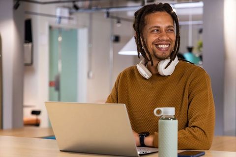 African american freelancer smiling while working on laptop in modern coworking space