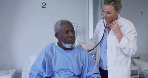 Doctor checking patient with stethoscope by hospital bed, clinical care consultation