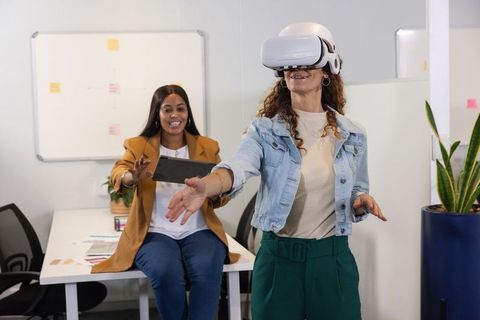 Diverse coworkers testing virtual reality headset for teamwork and product demo in office