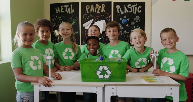 Group of diverse children learning about recycling in a classroom. They are wearing green shirts with recycling symbols and standing around a table with bins for metal, paper, and plastic. This is great for educational materials, school-related content, and promoting eco-friendly practices among young students.