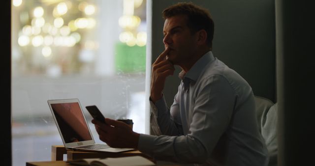 Thoughtful Businessman Contemplating While Using Smartphone and Laptop - Download Free Stock Images Pikwizard.com